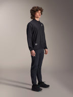Alpinestars A-Aria Windbreaker Jacket, Black, lightweight wind-resistant cycling jacket worn by a model with curly hair, featuring a white Astars logo on the chest and branding on the lower right, paired with black pants and shoes, performance fit for mountain biking and gravel riding