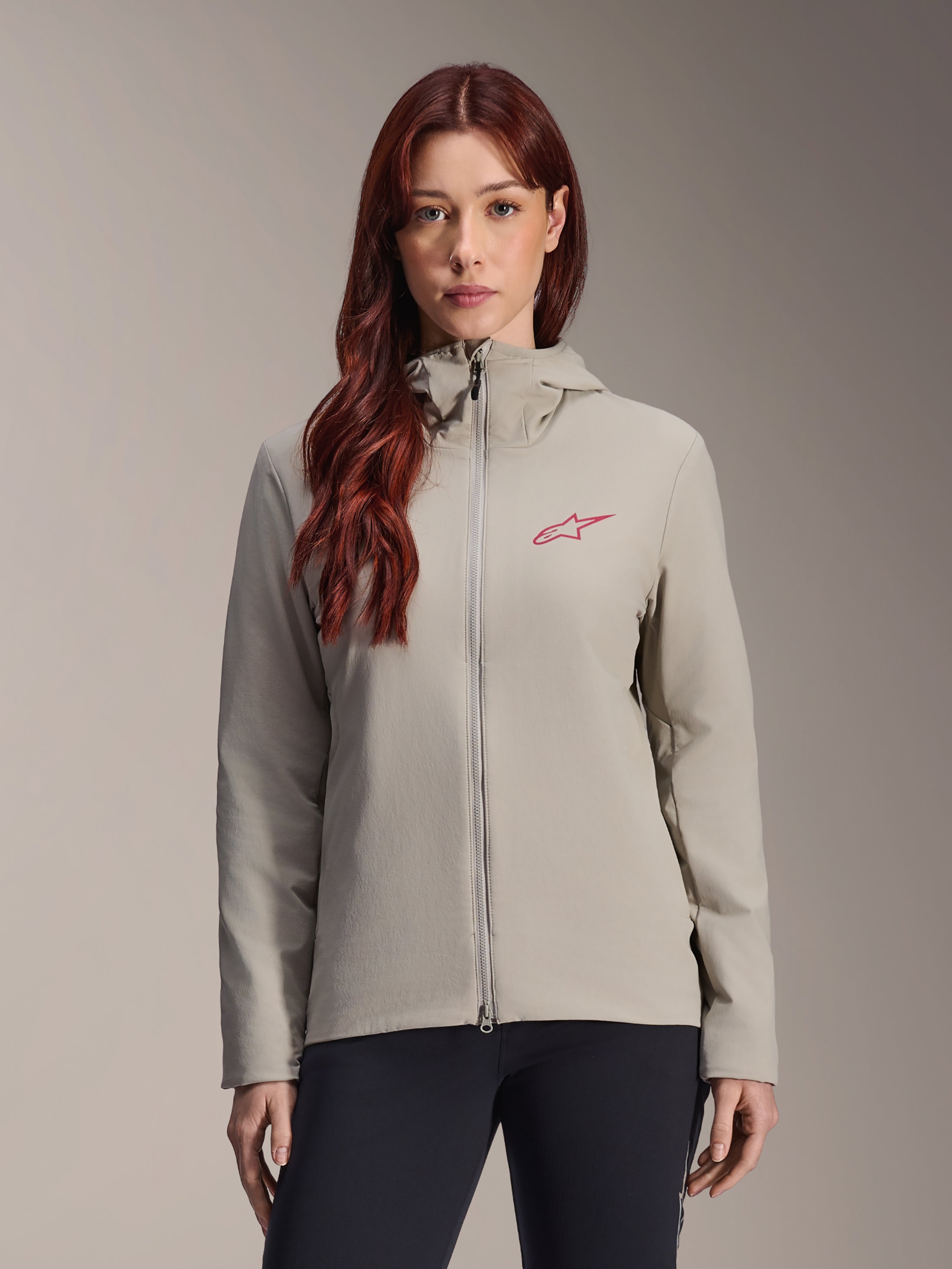 Alpinestars Stella A-Dura Thermal Jacket til kvinder, titaniumgrå, design med lynlås og hætte, rødt stjernelogo på brystet, kombineret med sorte bukser, livsstils-studioportræt