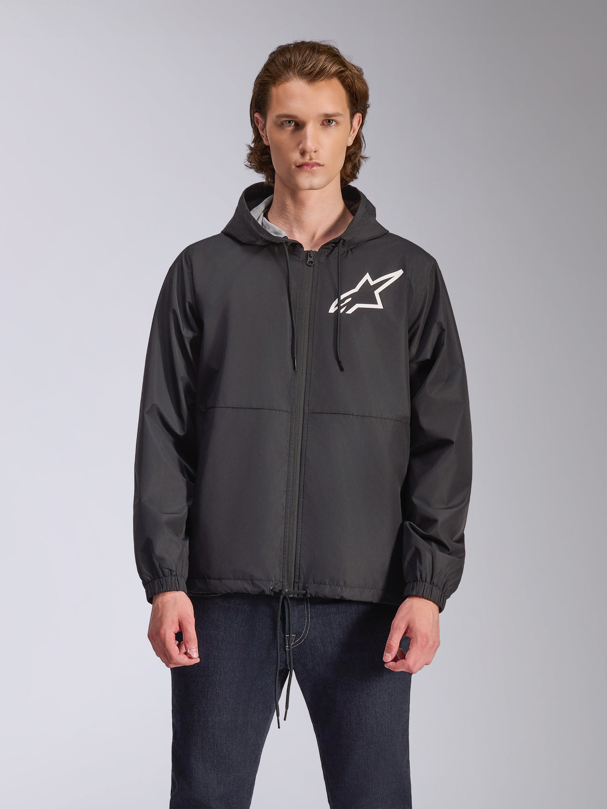 Alpinestars Speeder Chromium Windbreak Jacket, sort hættejakke med hvidt stjerne-logo på brystet, lynlås foran, hætte med snøre og elastiske manchetter, motorsport-inspireret casual streetwear