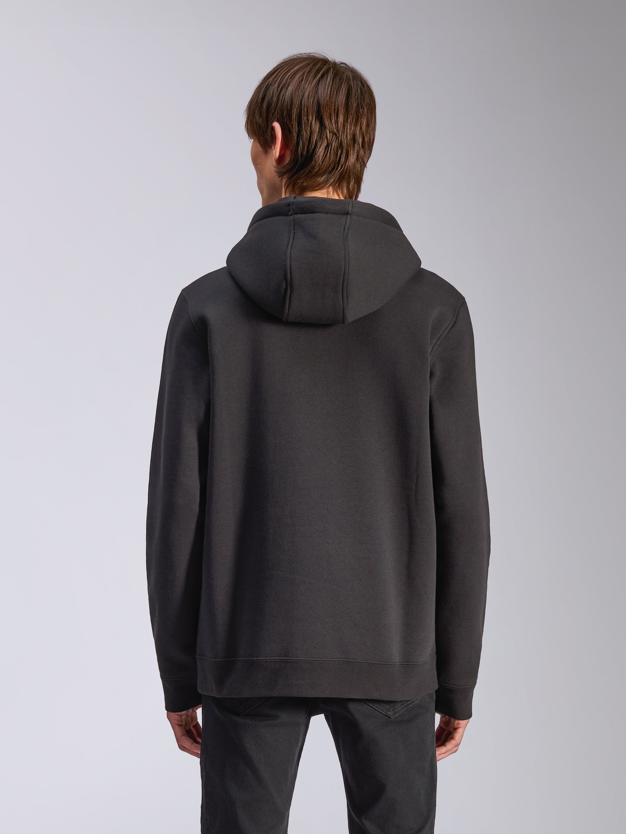 Alpinestars Harken hættetrøje, sort, mandlig model set bagfra iført afslappet fleece-pullover, ribmanchetter og kant, moderne motorsport-inspireret streetwear