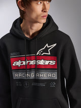 Alpinestars Harken Hoodie, sort pullover fleece-hættetrøje båret af en model, stor grafik på brystet med røde og grå striber, hvidt Alpinestars-ordmærke og stjernelogo, 'Racing Ahead'-tekst, moderne motorsport-inspireret afslappet streetwear.