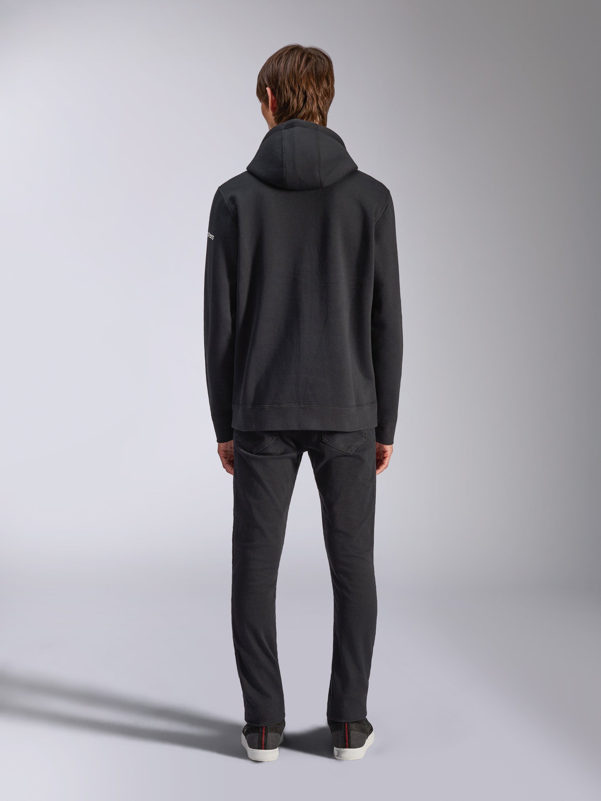 Alpinestars Frontal Hoodie, casual streetwear, sort, set bagfra af model iført pullover fleece-hættetrøje, med ribkant og manchetter, lille hvidt tekstlogo på ærmet, kombineret med sorte bukser