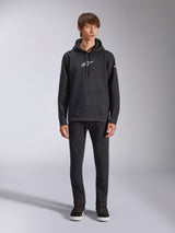 Alpinestars Frontal hættetrøje, sort pullover-fleecehættetrøje, hvidt Alpinestars-logo på bryst og ærme, kængurulomme, hætte med snoretræk, kombineret med sorte bukser, afslappet motorsport-inspireret design