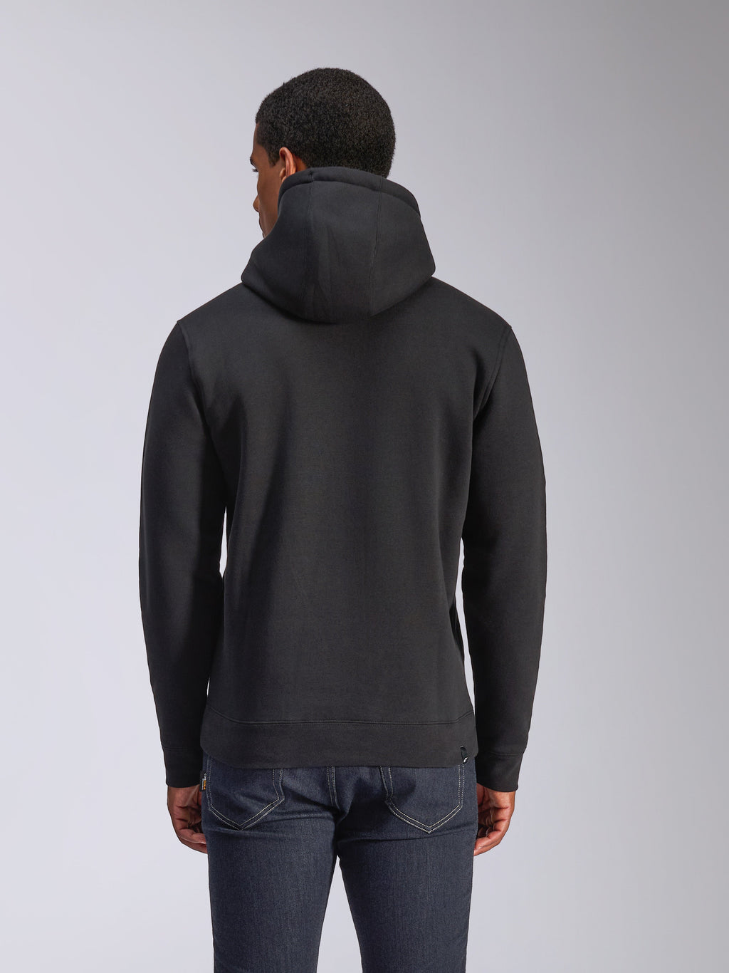 Alpinestars Blaze V3 Hættetrøje, sort pullover fleece-hættetrøje set bagfra, casual streetwear, med ribmanchetter og kant, jersey-foret hætte, båret med mørkeblå jeans