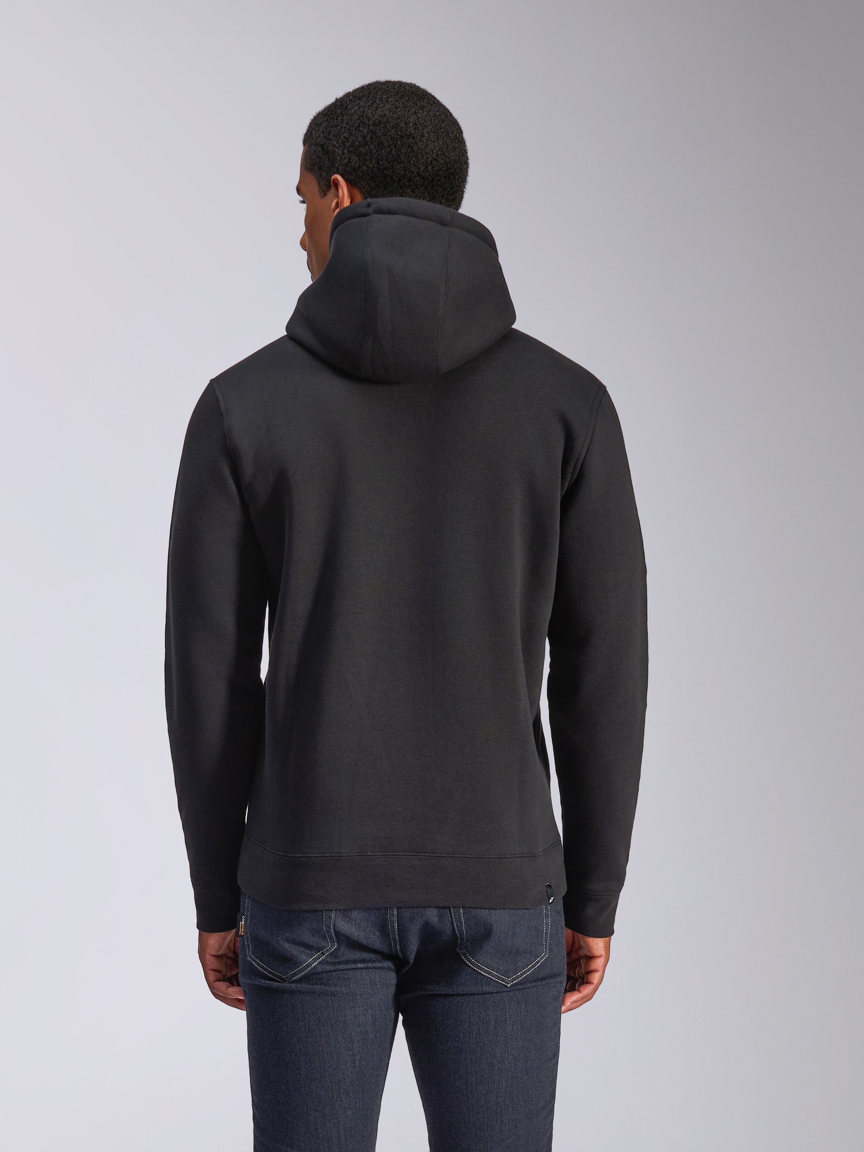 Alpinestars Blaze V3 Hættetrøje, sort pullover fleece-hættetrøje set bagfra, casual streetwear, med ribmanchetter og kant, jersey-foret hætte, båret med mørkeblå jeans