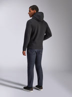Alpinestars Blaze V3 hættetrøje, set bagfra på en mand iført den sorte pullover-hættetrøje, kombineret med mørke jeans og sorte sneakers, afslappet motorsport-inspireret streetwear