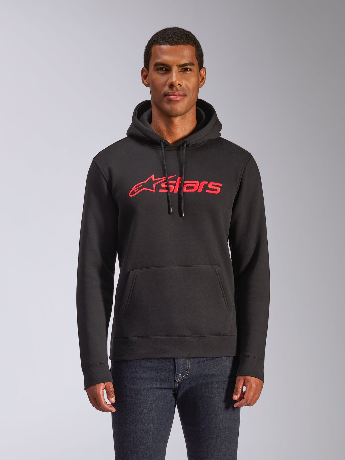 Alpinestars B l a ze V3 h æ t t e t r ø j e , f l e e c e - h æ t t e t r ø j e t i l m æ n d , s o r t m e d r ø d t A l p i n e s t a r s s t j e r n e - l o g o , b å r e t a f e n m a n d i m ø r k e j e a n s , m e d s n ø r e i h æ t t e n o g k æ n g u r u l o m m e , a f s l a p p e t m o t o r s p o r t - i n s p i r e r e t s t r e e t w e a r