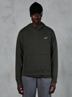 Alpinestars Essentials Ageless Hoodie, casual streetwear, Off Black pullover med et lille hvidt Alpinestars-logo på brystet, båret med en sort beanie, minimalistisk design med kængurulomme og stenvasket finish