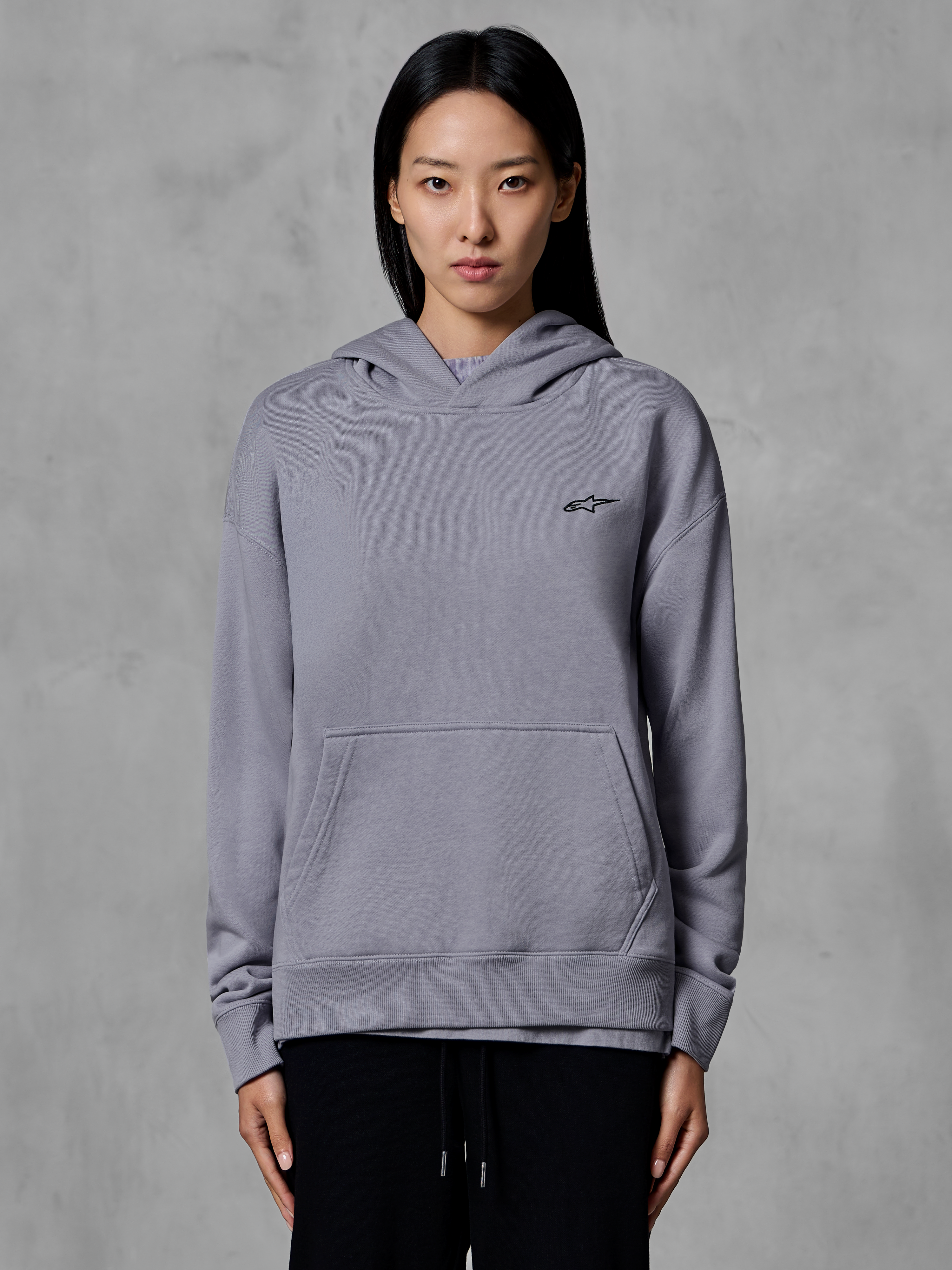 Alpinestars Essentials Ageless Hoodie, afslappet sportstøj, sølvfarvet med lille sort logo, kængurulomme, hættetrøje, båret af model, moderne livsstilsbeklædning