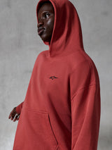 Alpinestars Essentials Ageless hættetrøje, afslappet sportstøj, teglrød, bæres af en model med hætten oppe, lille sort broderet logo, blød fleece-tekstur, afslappet pasform streetwear