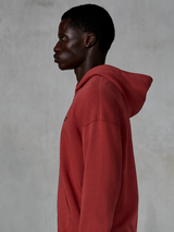 Alpinestars Essentials Ageless Zip Hoodie, teglrød, sideprofil af en mand iført en hættetrøje med lynlås i afslappet pasform, lille sort stjernelogo på brystet, premium stone-washed fleece, afslappet motorsport-inspireret streetwear