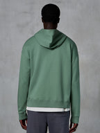 Alpinestars Essentials Ageless Zip Hoodie, set bagfra på model, Cactus-grøn, afslappet motorsport-inspireret streetwear, afslappet pasform med ribkant ved søm og manchetter, kompakt fleece af høj kvalitet