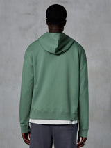 Alpinestars Essentials Ageless Zip Hoodie, set bagfra på model, Cactus-grøn, afslappet motorsport-inspireret streetwear, afslappet pasform med ribkant ved søm og manchetter, kompakt fleece af høj kvalitet