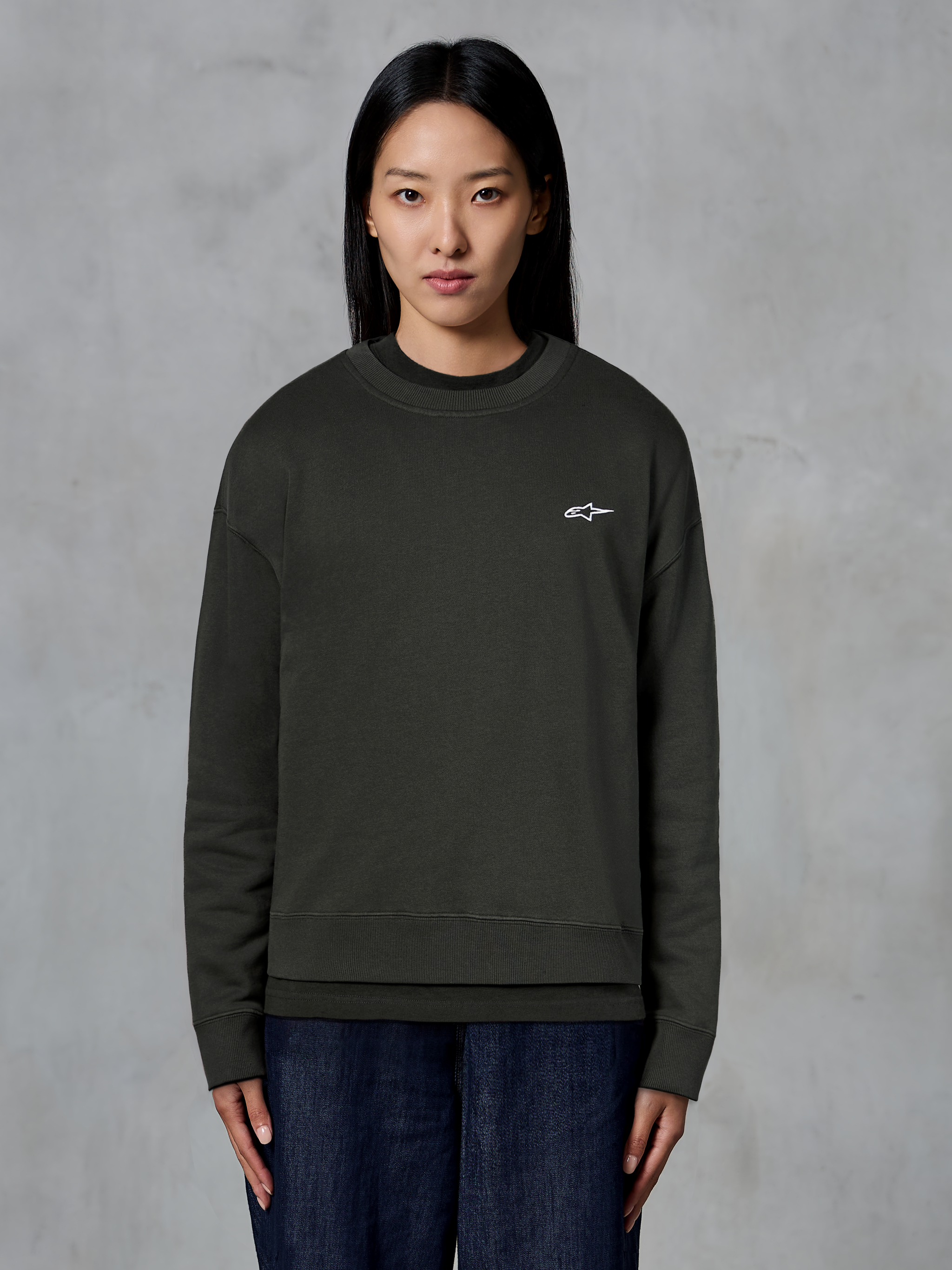 Alpinestars Essentials Ageless Crew, premium crewneck sweatshirt, Off Black, med et lille hvidt Alpinestars-logo på brystet, afslappet streetwear-stil båret af en model med mørke jeans