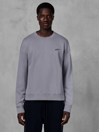 Alpinestars Essentials Ageless Crew, sølvfarvet crewneck sweatshirt båret af en model, med et lille sort stjernelogo på brystet, afslappet pasform med ribbede manchetter og kant, afslappet motorsport streetwear