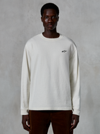 Alpinestars Essentials Ageless LS Tee, langærmet T-shirt, råhvid, lille sort stjernelogo på brystet, afslappet streetwear, afslappet pasform, båret af en model