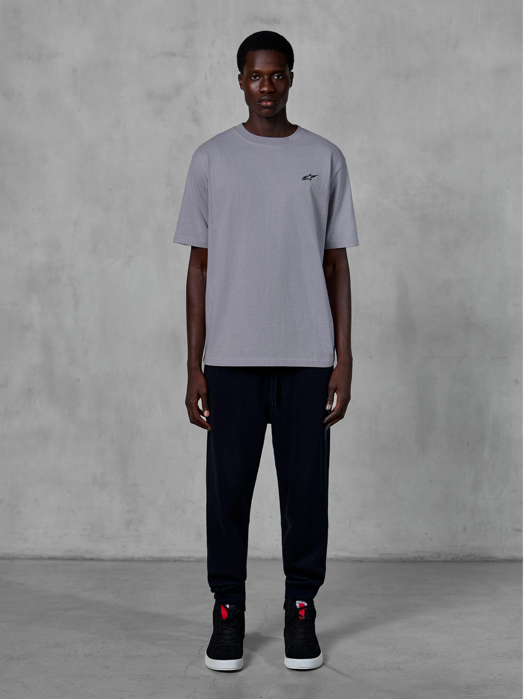 Alpinestars Essentials Ageless SS Tee, kortærmet t-shirt, Silver, med et lille sort logo på brystet, stylet med sorte joggingbukser og sneakers, afslappet motorsport streetwear