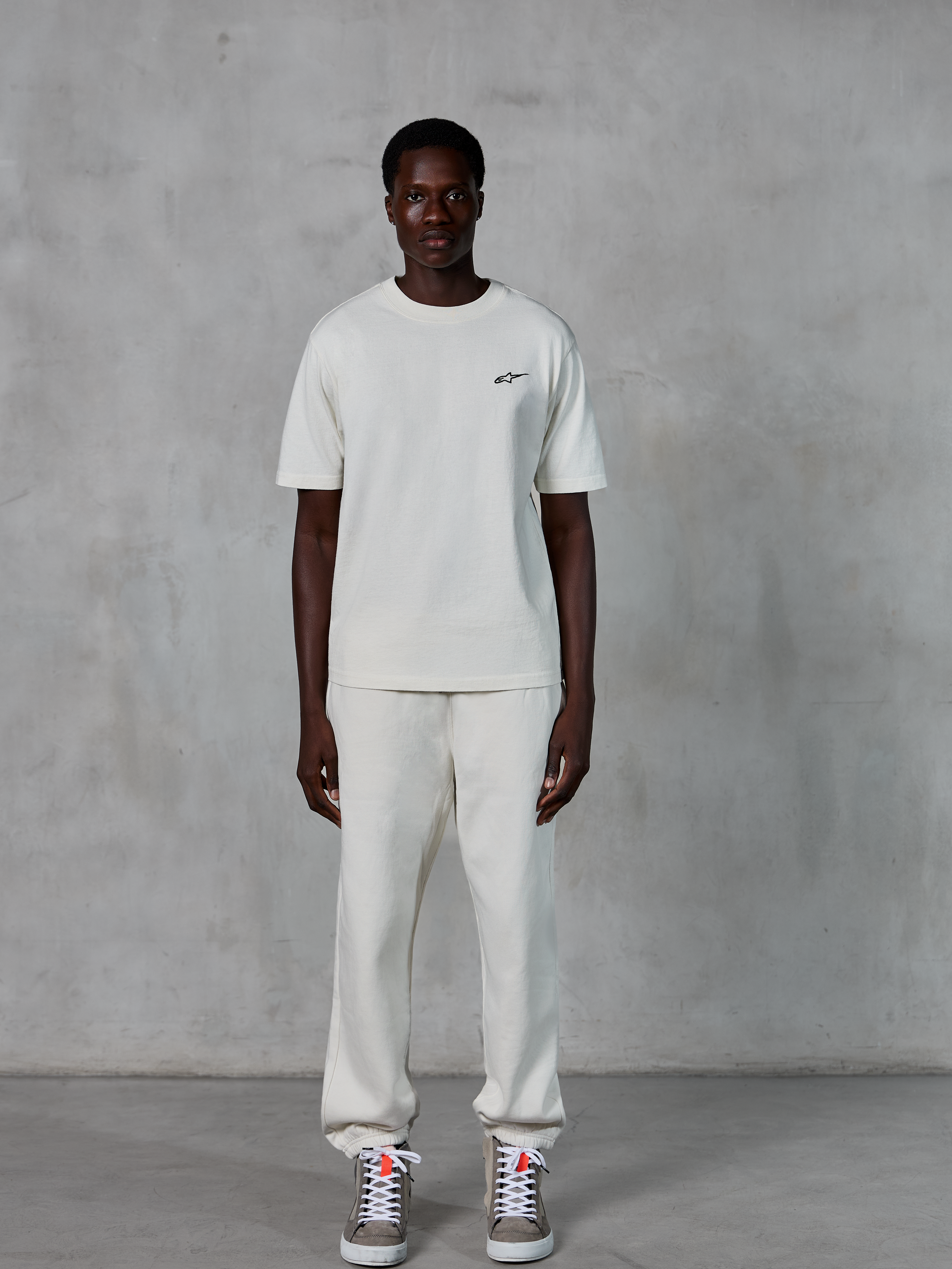 Alpinestars Essentials Ageless SS Tee, kortærmet T-shirt, råhvid, med et lille sort Alpinestars-logo på brystet, stylet med matchende joggingbukser og sneakers for et afslappet livsstilslook