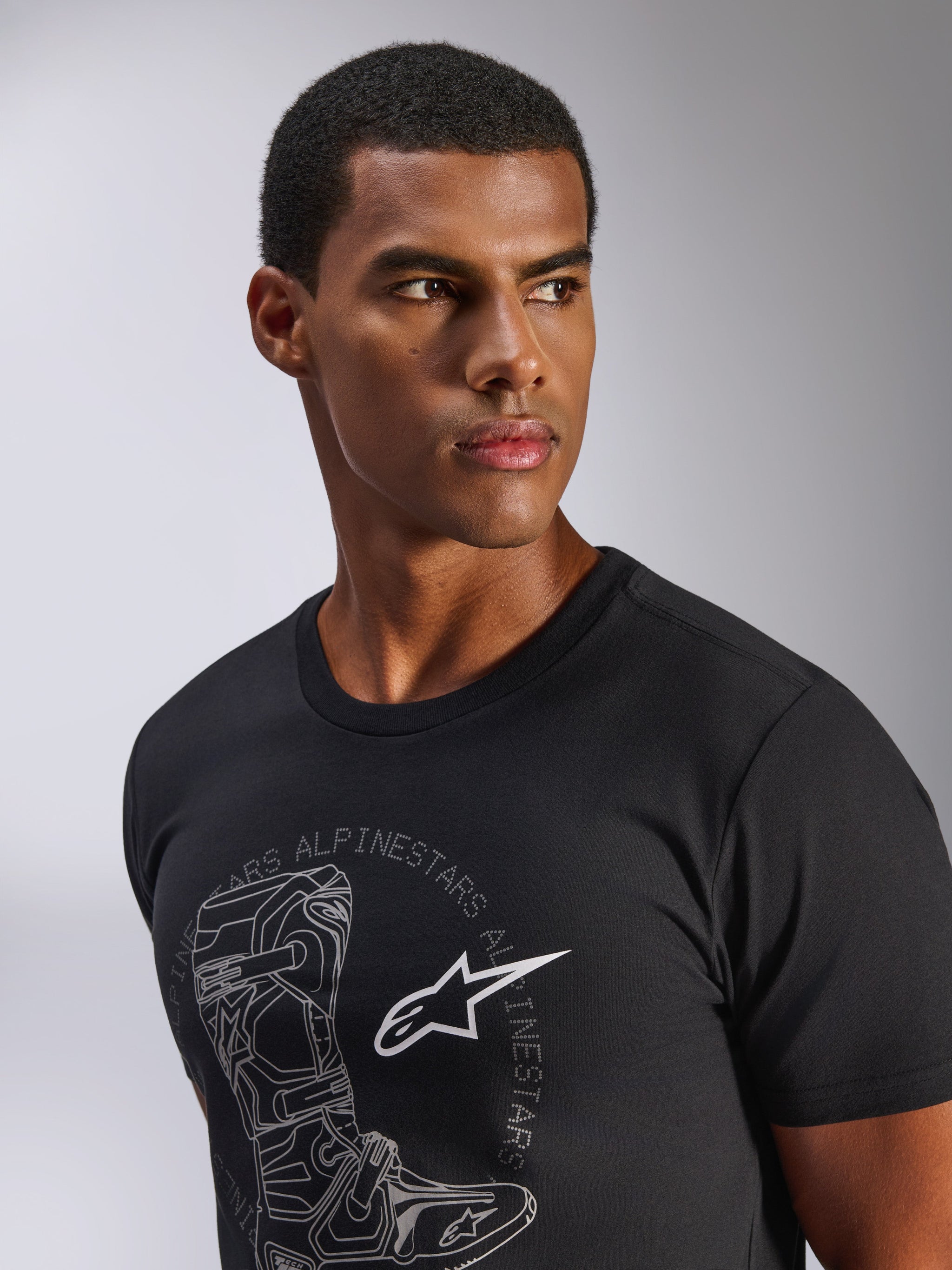 Alpinestars Tech Boot CSF Tee, kortærmet t-shirt, sort, grå Tech Boot-grafik med hvidt Astars-logo, båret af en mandlig model, casual motorsport streetwear