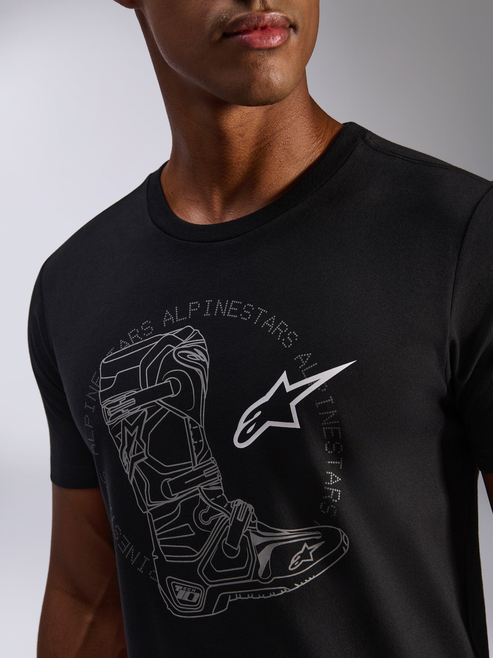Alpinestars Tech Boot CSF Tee, kortærmet t-shirt, sort, med en stor grafik af en tech-støvle, cirkulært Alpinestars-ordmærke og hvidt stjernelogo, casual motorsport streetwear