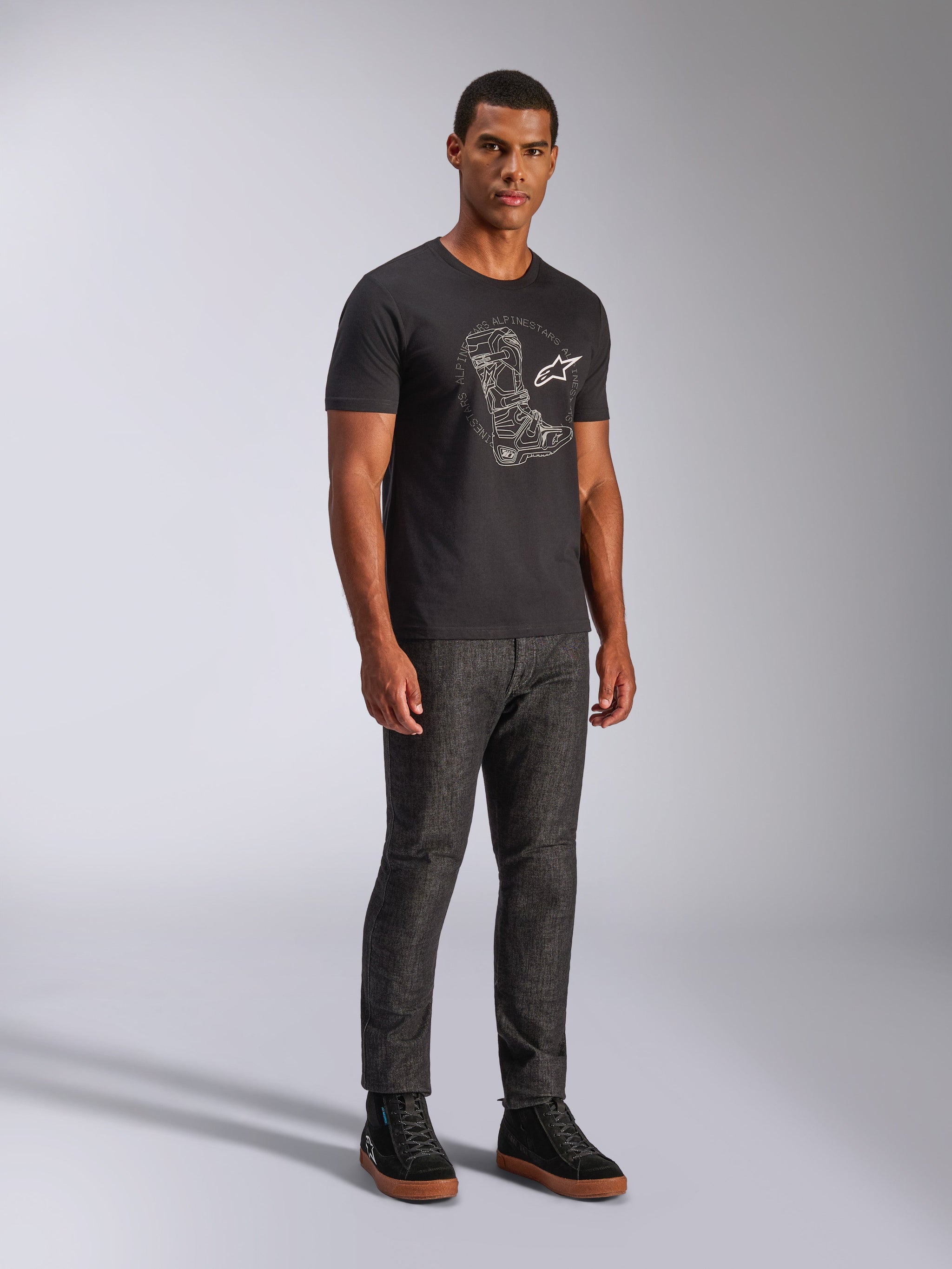 Alpinestars Tech Boot CSF Tee, kortærmet t-shirt, sort, med hvid grafik af en tech boot og logo på brystet, båret af en model med mørke denimbukser og sorte sneakers, afslappet motorsport-inspireret streetwear