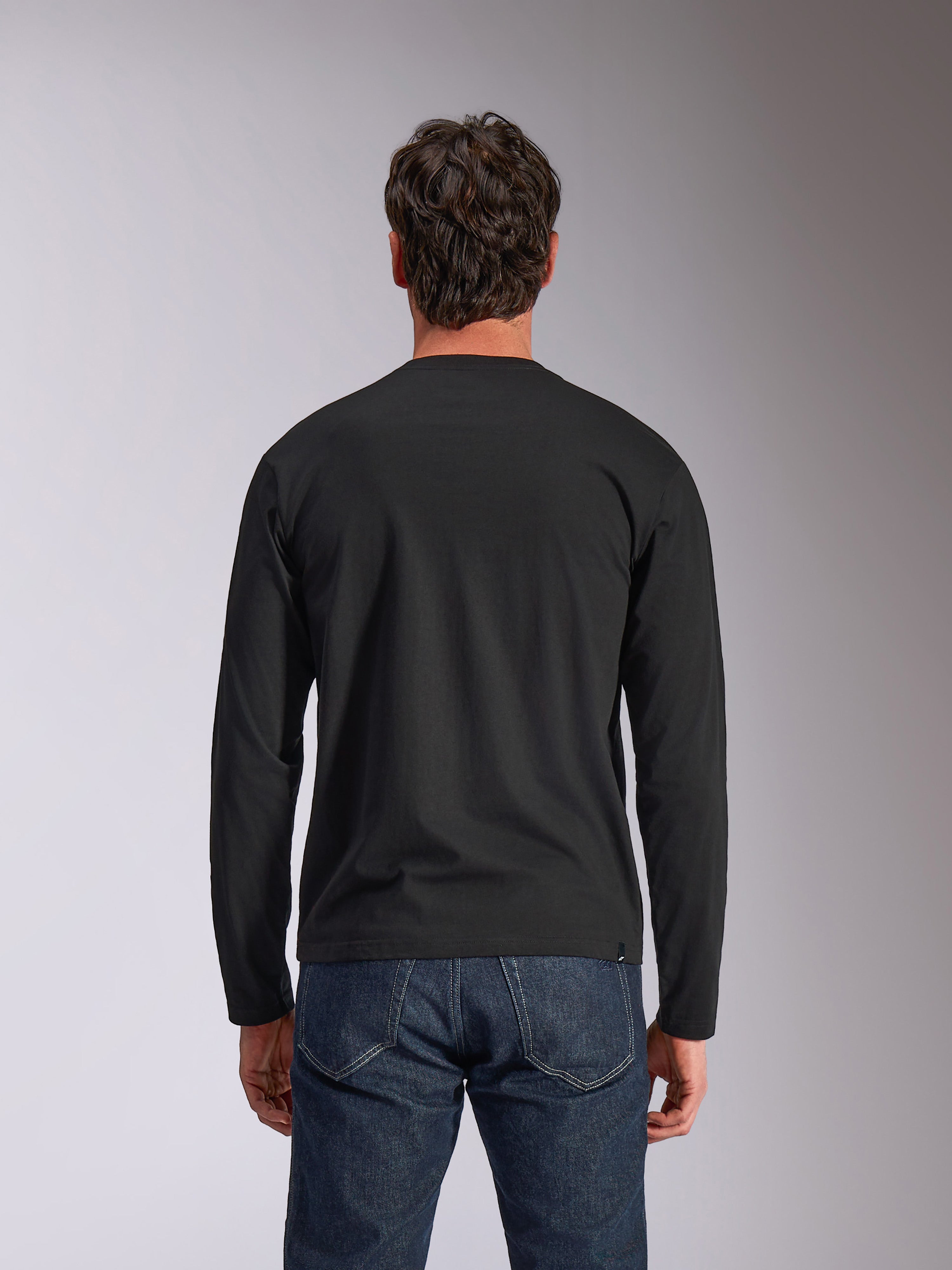 Alpinestars Trackside CSF Tee, langærmet t-shirt, sort, set bagfra, båret med mørkeblå denimjeans, afslappet motorsport-inspireret streetwear