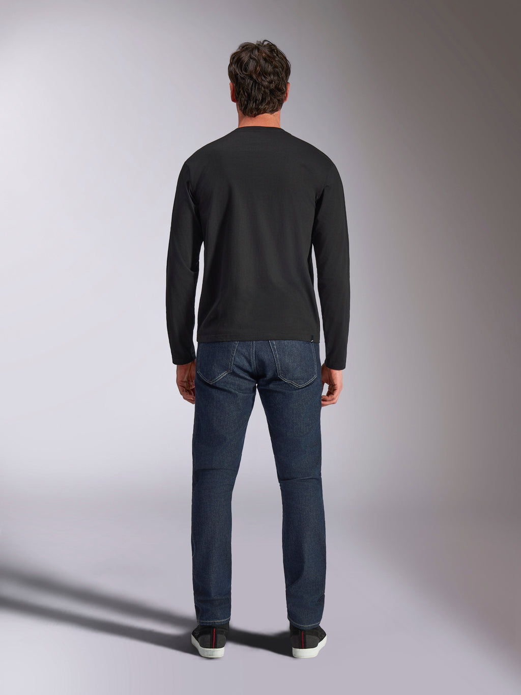 Alpinestars Trackside CSF Tee, langærmet t-shirt, sort, set bagfra på en model iført mørkeblå denimjeans, afslappet motorsport streetwear