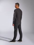 Alpinestars Trackside CSF Long Sleeve Tee, Black, featuring large grey Alpinestars logo on the left sleeve, worn by model with black pants and casual sneakers, motorsport-inspired casual streetwear.