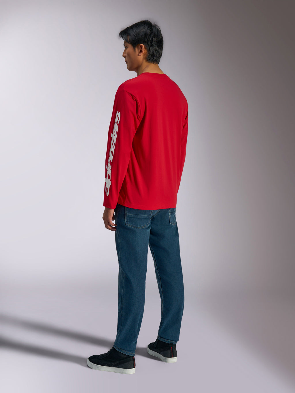 Alpinestars Trackside CSF Tee, langærmet t-shirt, rød, med et hvidt lodret Alpinestars-logo på ærmet, båret af en model med blå jeans og sorte sneakers, afslappet motorsport-inspireret streetwear