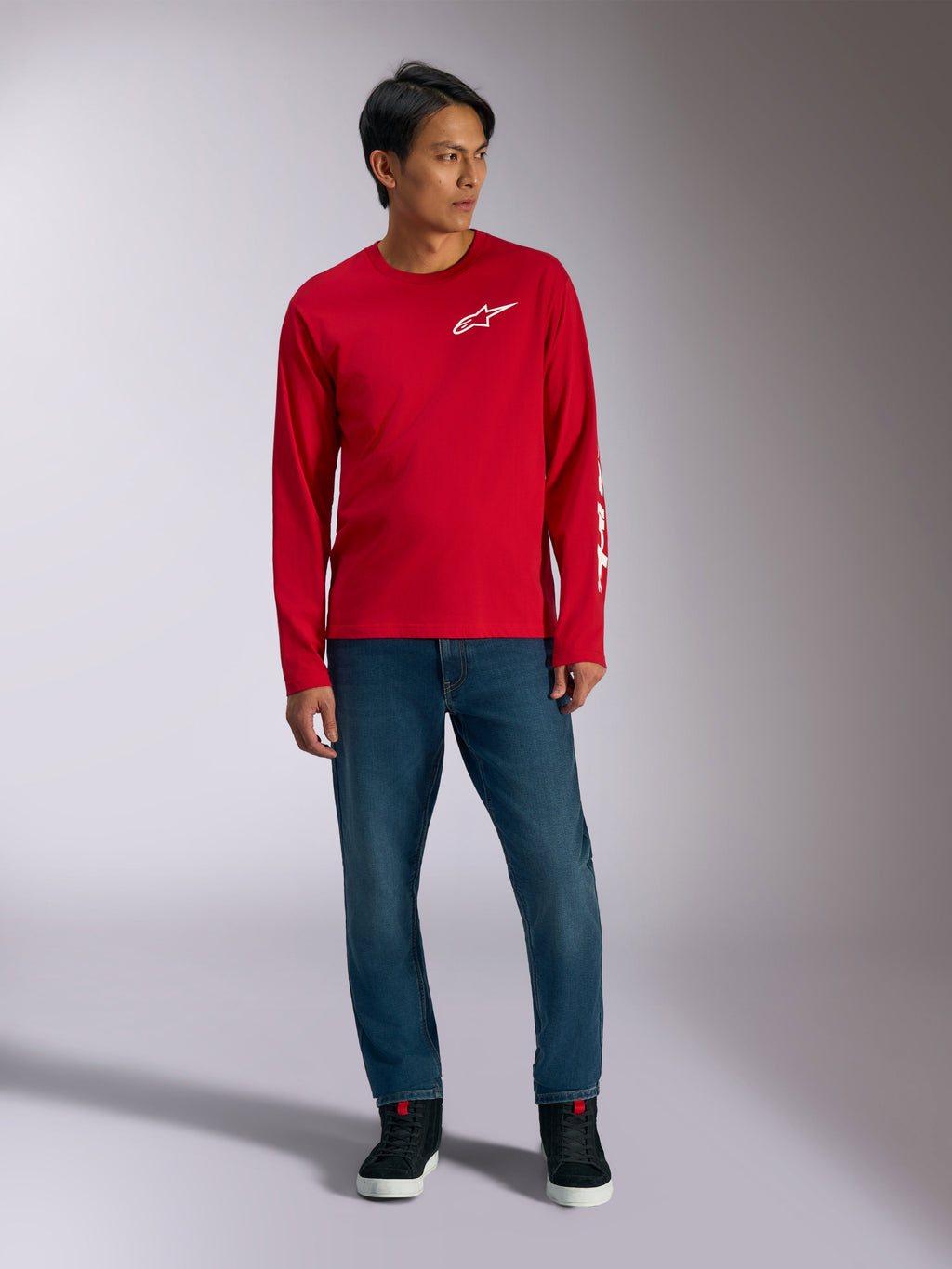 Alpinestars Trackside CSF Tee, langærmet t-shirt, rød med hvidt Alpinestars-logo, livsstilsbillede båret med blå jeans og sorte sneakers, afslappet motorsport-inspireret sportstøj