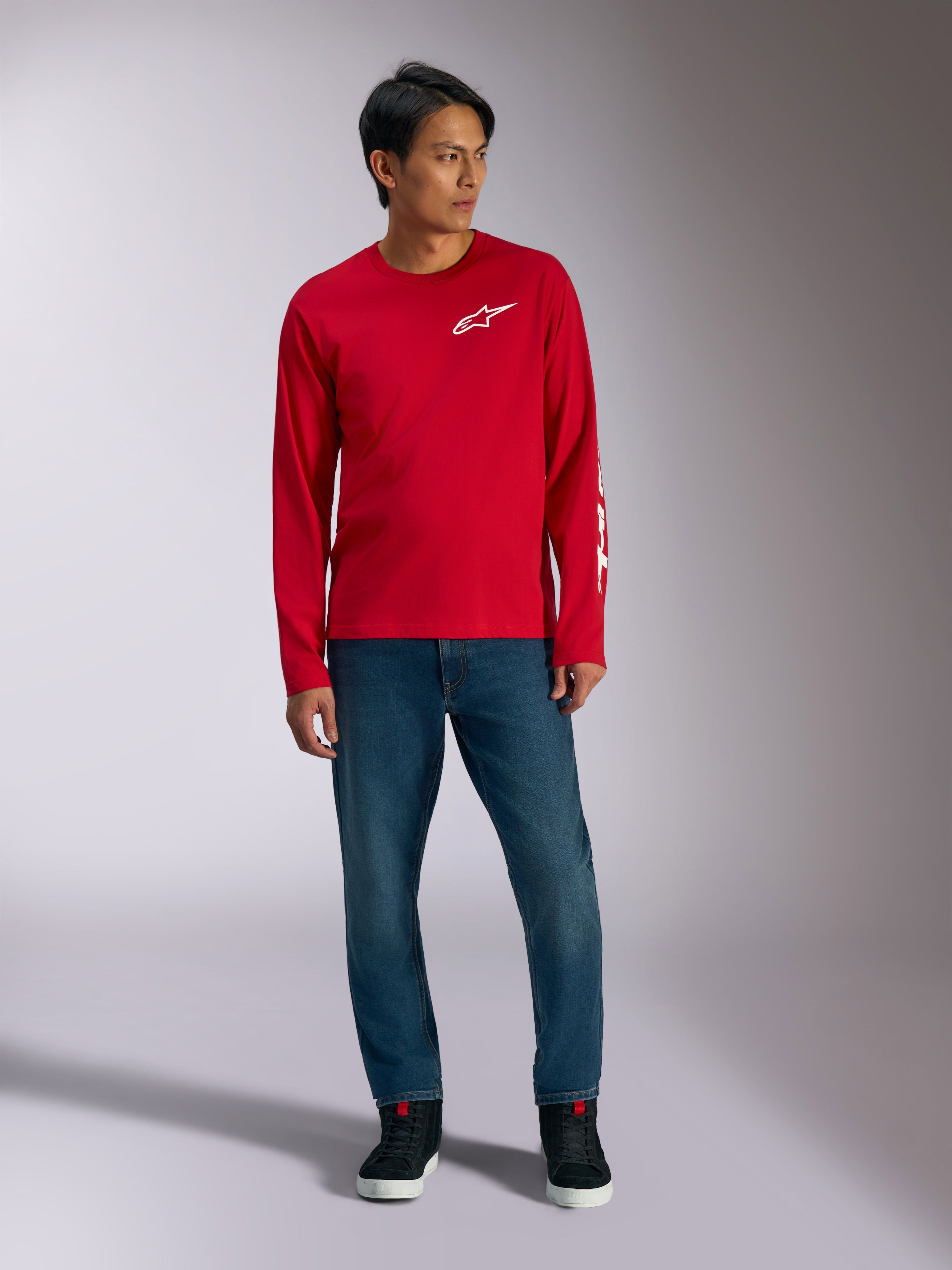 Alpinestars Trackside CSF Tee, langærmet t-shirt, rød med hvidt Alpinestars-logo, livsstilsbillede båret med blå jeans og sorte sneakers, afslappet motorsport-inspireret sportstøj