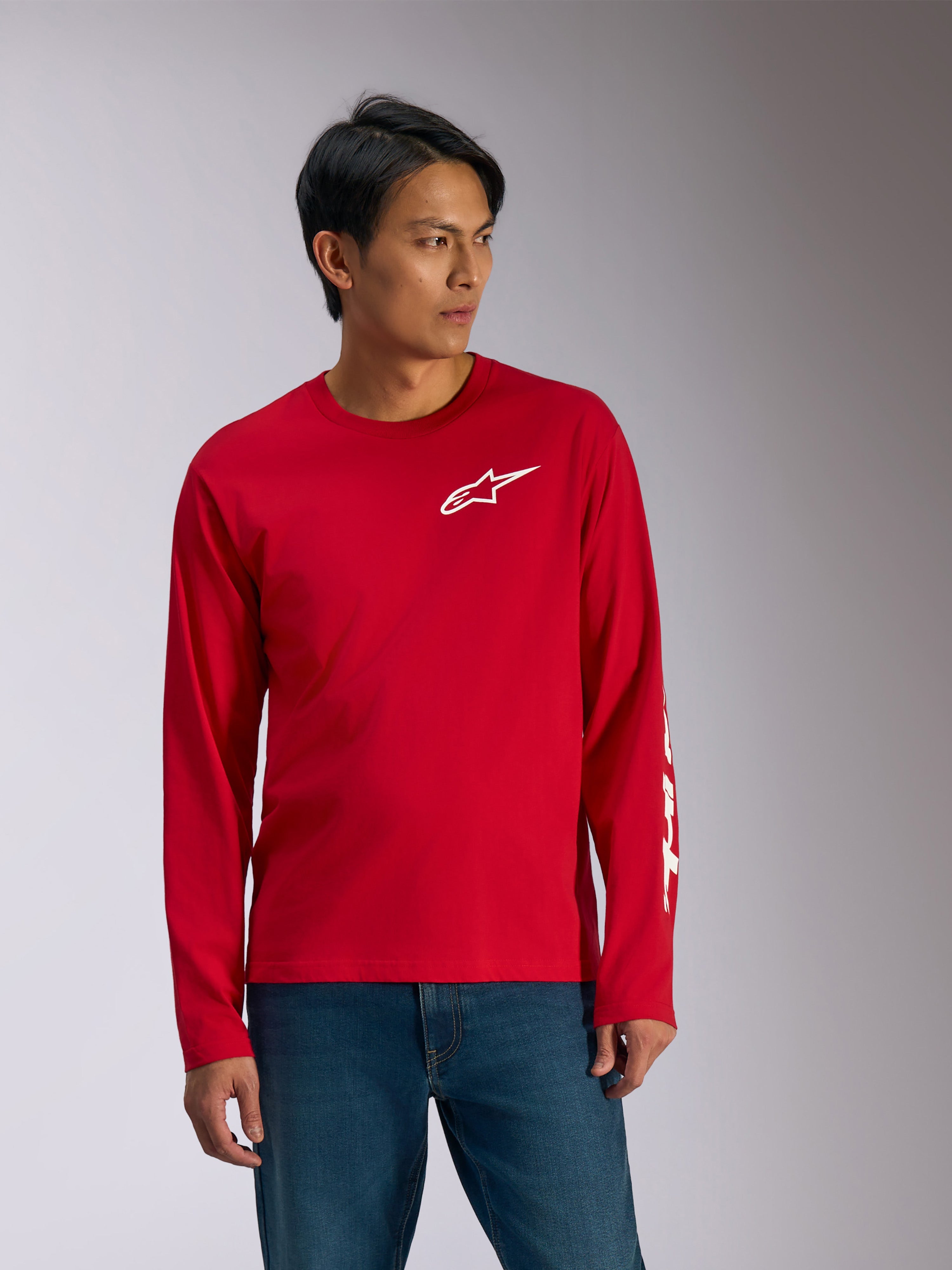 Alpinestars Trackside CSF Tee, langærmet t-shirt, rød med hvid grafik, hvidt Alpinestars stjernelogo på brystet og hvid tekst på ærmet, båret med blå jeans, afslappet motorsport-inspireret sportstøj