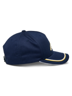 Alpinestars Ascension Snapback kasket, set fra siden, marineblå med guld og hvid sutache-kant på den buede skygge, struktureret krone, afslappet motorsport-hovedbeklædning