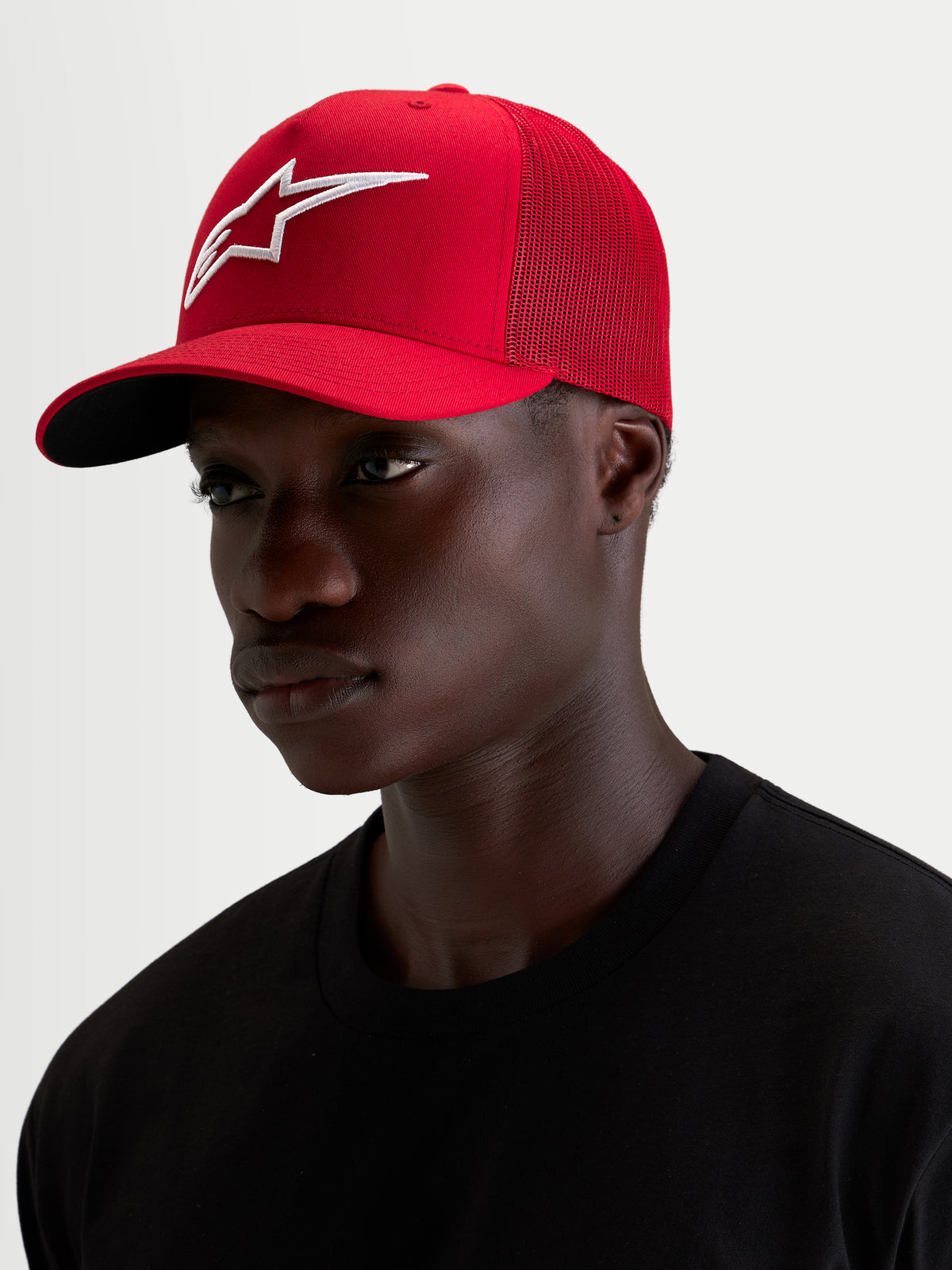Alpinestars Ageless Snapback kasket, rød og hvid sportswear-kasket med buet skygge og 3D-broderet Astars-logo, båret af mandlig model