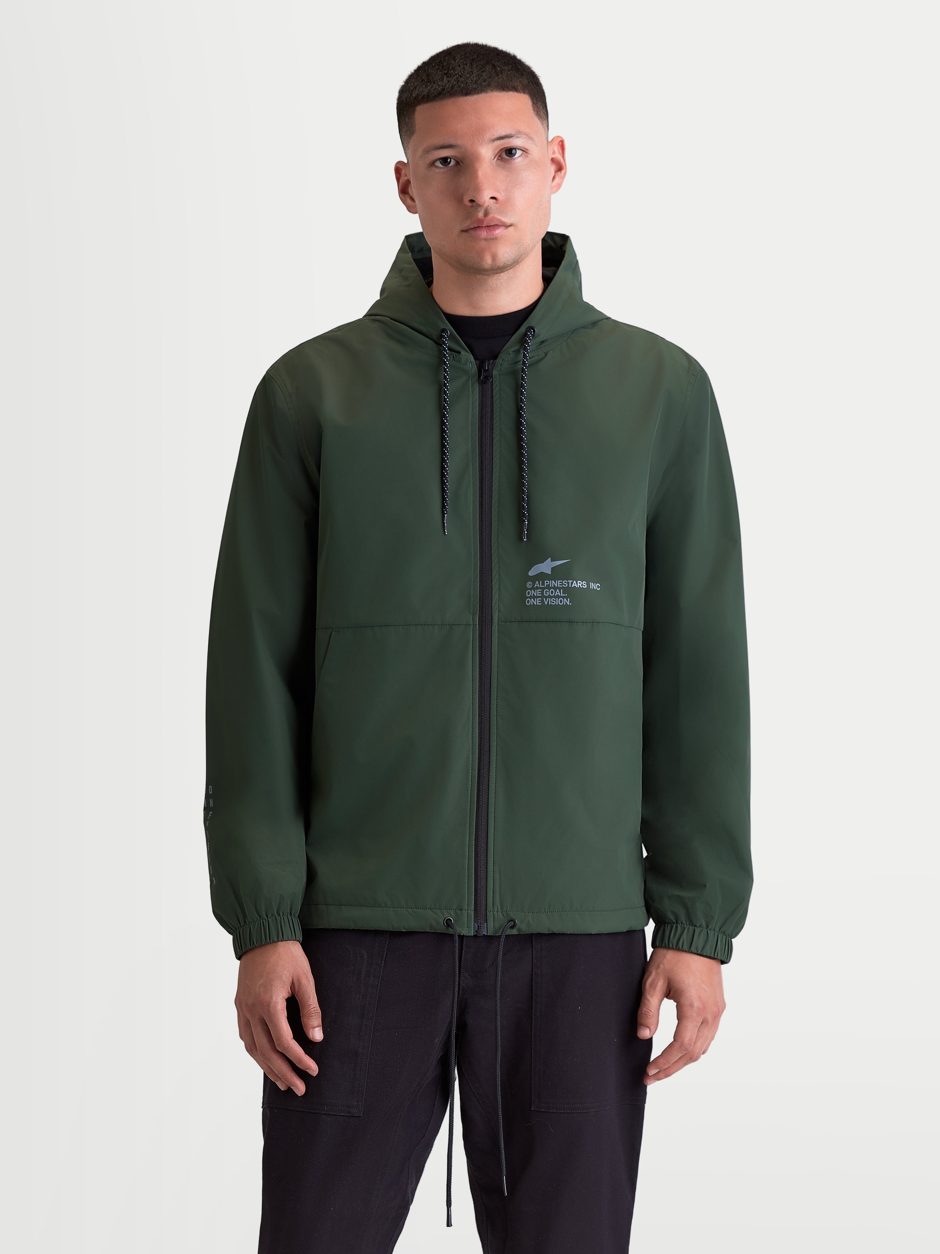 Alpinestars Speeder Resolve Windbreaker Jakke, let sportswear til bybrug, grøn herrejakke med hætte, mesh-foret inderside, justerbar hætte med snoretræk og lynlås foran, signatur Alpinestars-branding på brystet, set forfra på model.