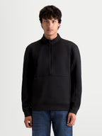 Alpinestars Apera Half-Zip sweatshirt, sort unisex sportswear-pullover i fleece, kængurulomme og halvlynlås, tonalt HD-logotryk, motorsport-inspireret design til hverdagsbrug, vist på model.