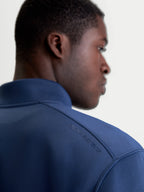 Alpinestars Apera Half-Zip sweatshirt, sportswear-pullover i blå, nærbillede bagfra på model der viser tonalt HD-logotryk på skulderen og premium tri-blend fleece.