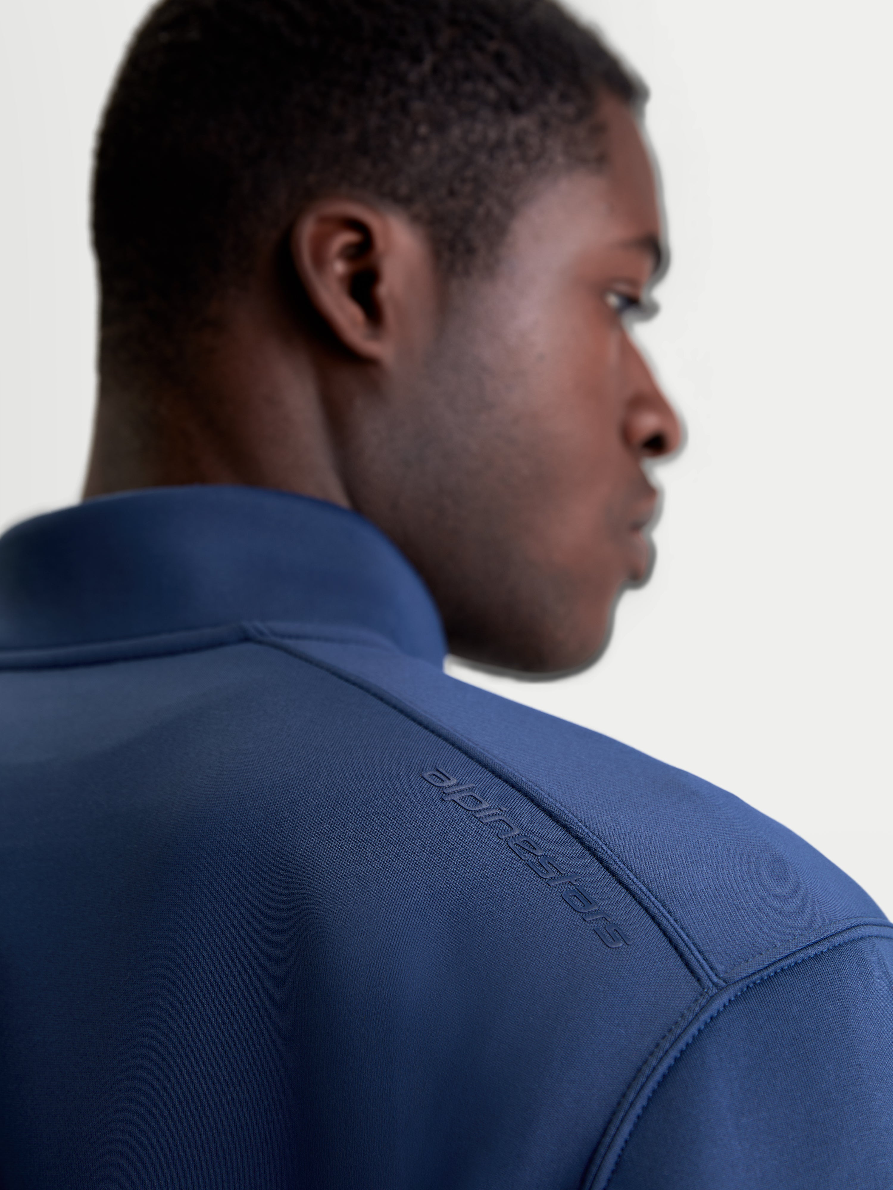 Alpinestars Apera Half-Zip sweatshirt, sportswear-pullover i blå, nærbillede bagfra på model der viser tonalt HD-logotryk på skulderen og premium tri-blend fleece.