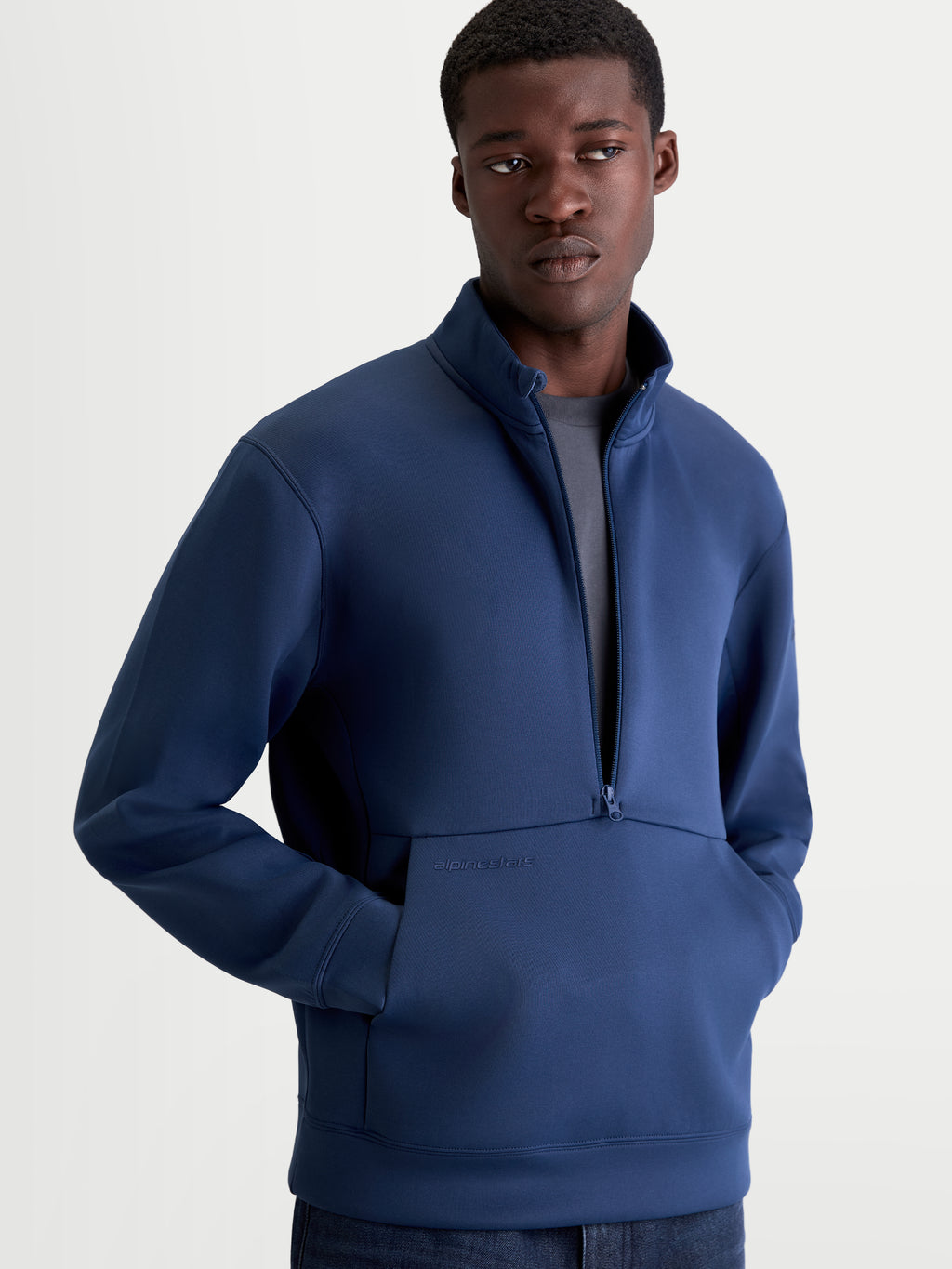 Alpinestars Apera Half-Zip sweatshirt, blå herre-sportswear pullover vist på model, med halv lynlås, kængurulomme med tonalt logo og meshforet hætte, premium tri-blend fleece til hverdagsbrug.