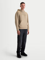 Alpinestars Datrix hættetrøje, brun pullover til herre med tonalt HD-logo, mesh-foret hætte og frontlomme med indsnitsdetaljer, afslappet motorsport-inspireret sportstøj vist på model.
