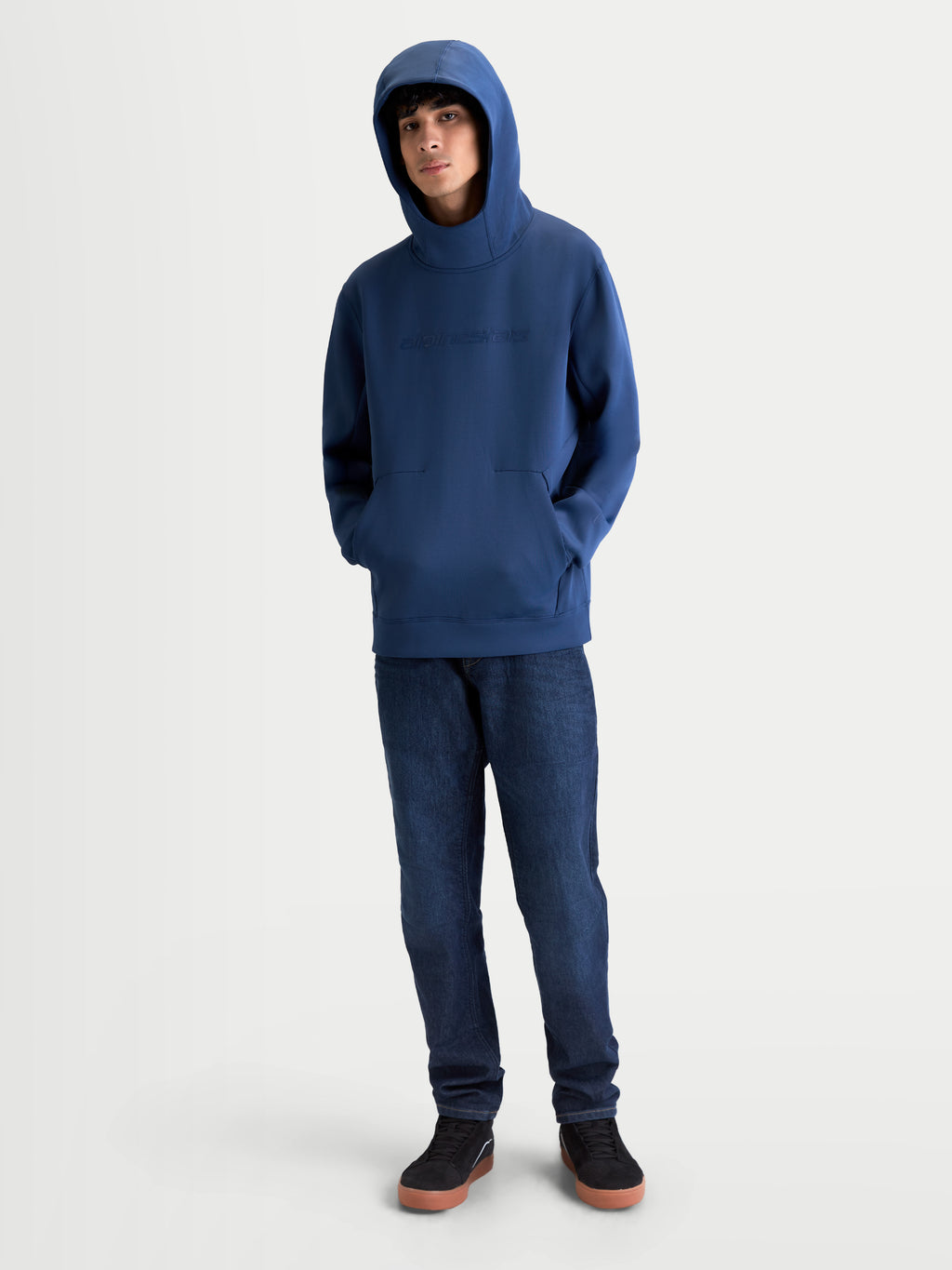 Alpinestars Datrix hættetrøje, motorsportsinspireret pullover i stålblå, premium tri-blend fleece med tonalt HD-logo på brystet og mesh-foret hætte båret oppe af en model.