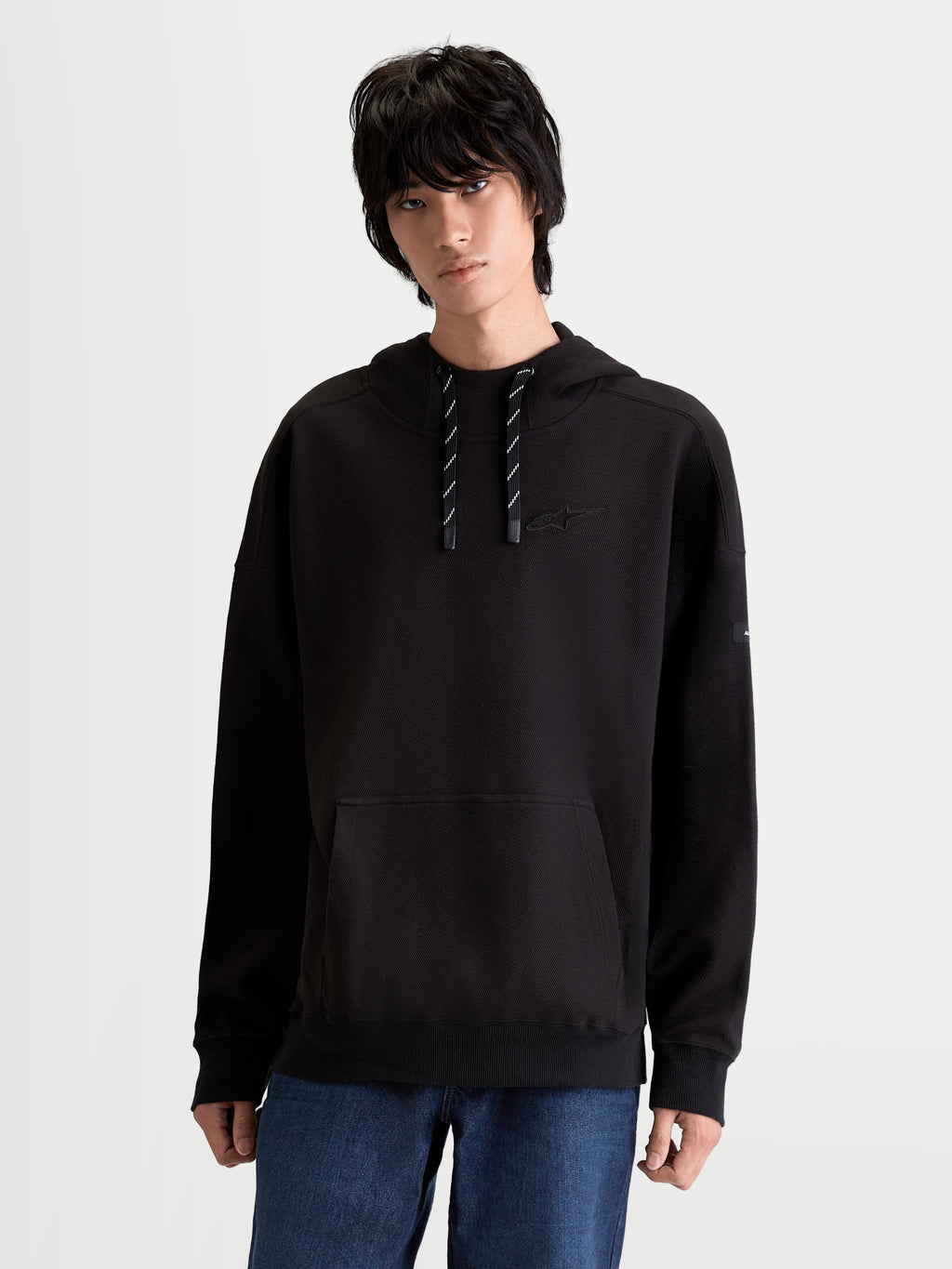 Alpinestars Camino Textured Oversized hættetrøje, sportstøj livsstilspullover, sort, tekstureret strikket twill-fleece med høj krave, kængurulomme og tonalt broderet logo på brystet.