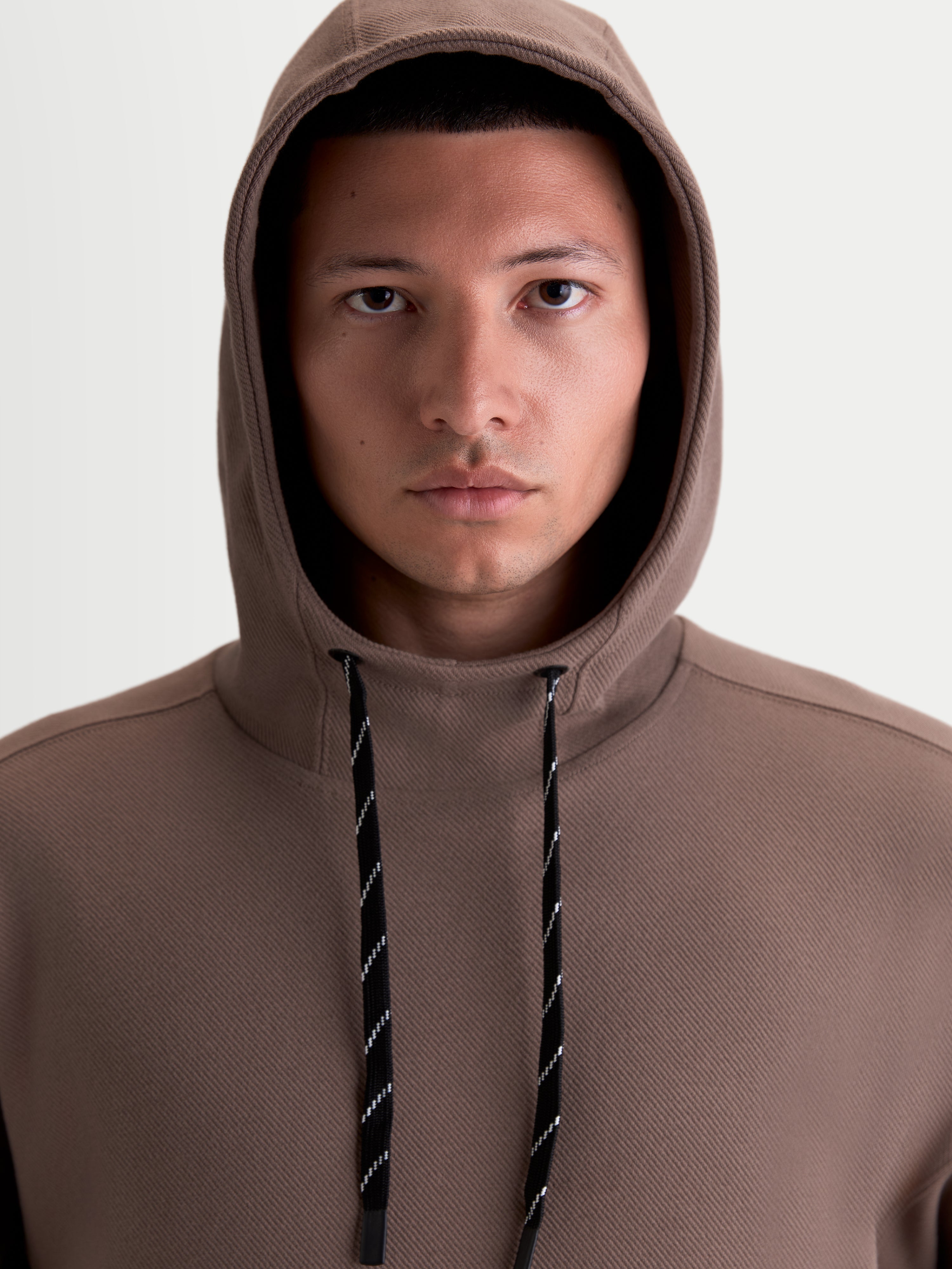 Alpinestars Camino Textured Oversized hættetrøje, brun casual sportswear pullover til herrer og damer, tekstureret strikket twill-fleece, høj krave og hætte med sort-hvide mønstrede snører.