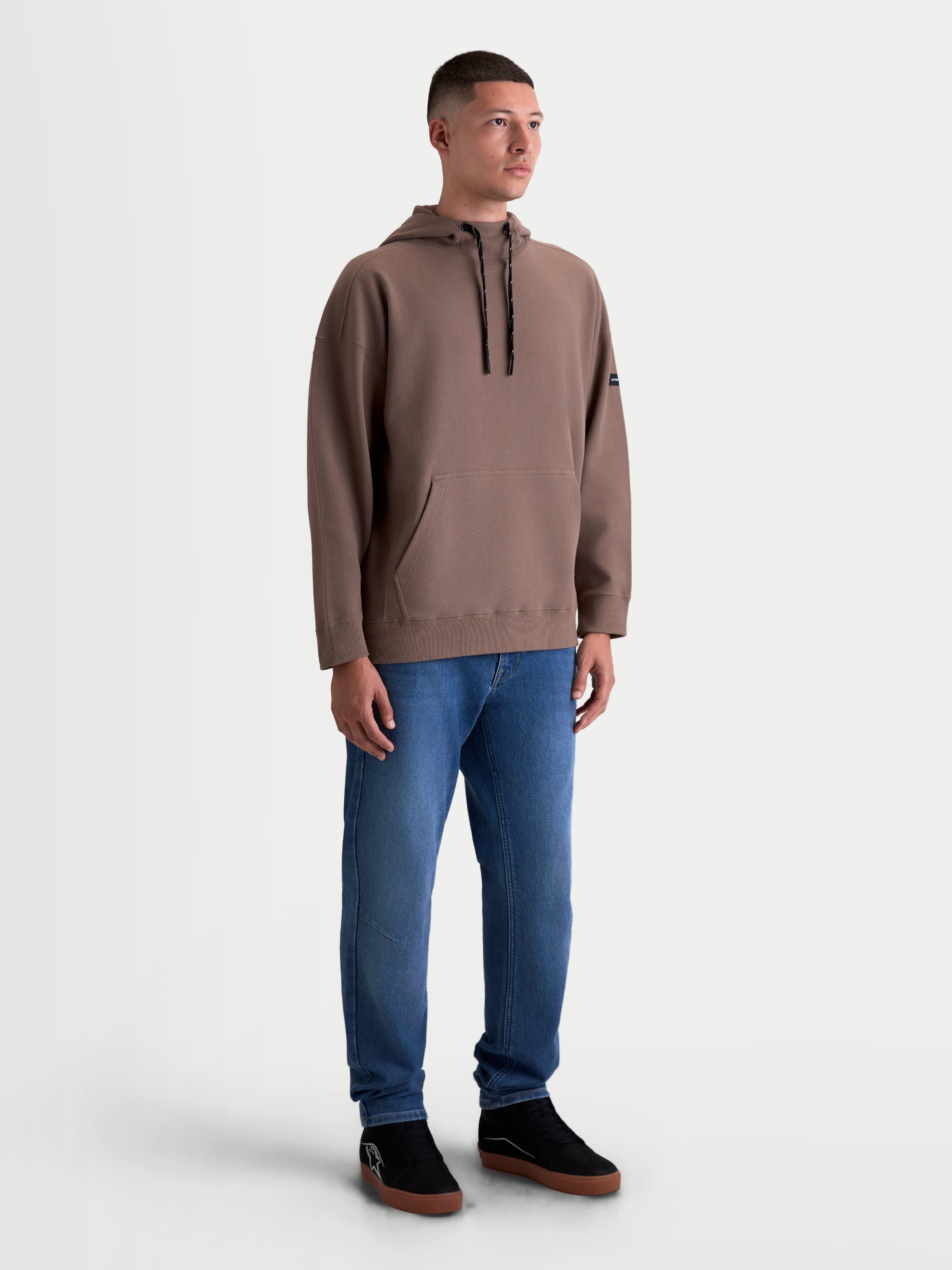 Alpinestars Camino Textured Oversized hættetrøje, afslappet sportstøj til herrer, brun, tekstureret strikket twill-fleece, høj krave og kængurulomme, oversized pasform, vist på model.