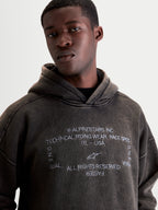 Alpinestars Infinite Washed Oversized hættetrøje, herrehættetrøje i vasket sort med snevasket finish, hvidt grafisk logo- og teksttryk på brystet, afslappet hverdagsfleece og motorsport-inspireret sportswear.