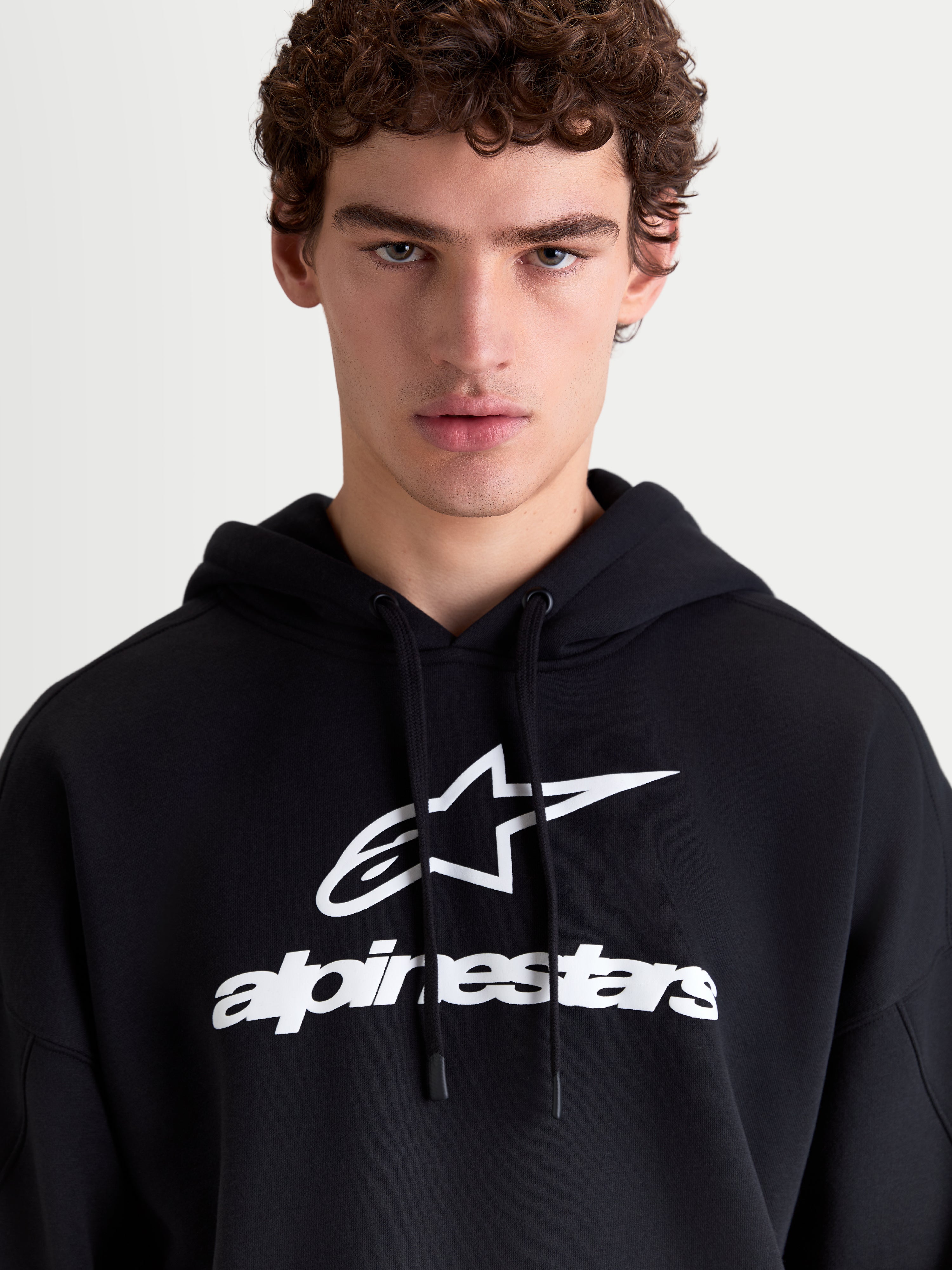 Alpinestars Prelude Oversized hættetrøje til herrer, sort og hvid fleece-pullover med hvidt puff-printet logo på brystet, oversized pasform, afslappet sportswear til hverdagsbrug.