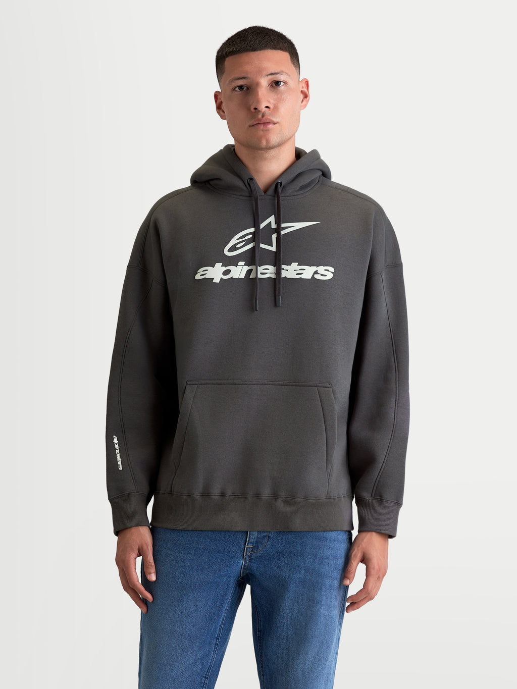 Alpinestars Prelude Oversized hættetrøje, herre-sportswear fleece-pullover, mørkegrå og hvid, bomuld og genanvendt polyester, afslappet oversized pasform, kængurulomme og markante puff-printede logoer på brystet og ærmet.
