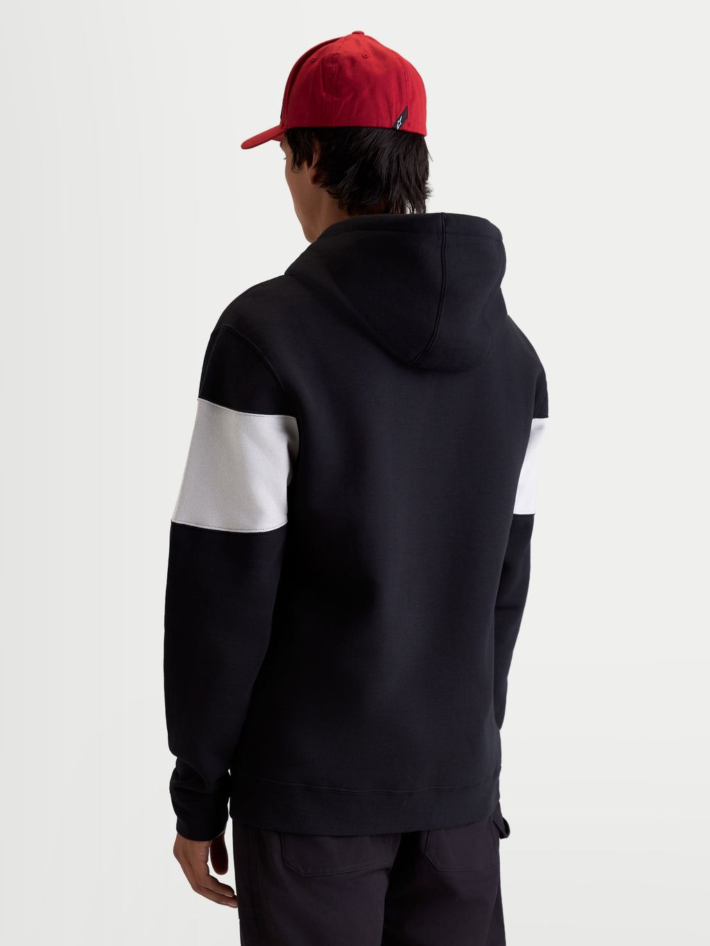 Alpinestars Cubic hættetrøje, sportswearhættetrøje i fleece, sort og hvid, farveblokeret design på ærmerne, bomuld og genanvendt polyester, set bagfra på model i afslappet hverdagsstil.