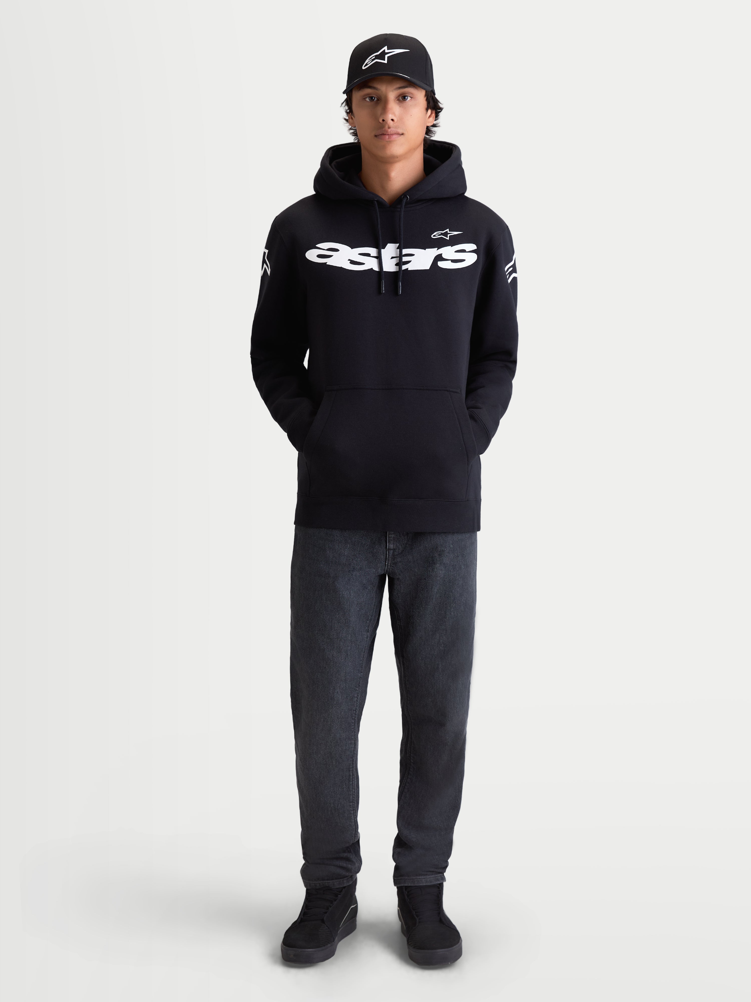 Alpinestars Velocifier hættetrøje, herrehættetrøje i sort fleece, afslappet sportstøj til hverdagsbrug, hvidt Astars-tekstlogo på brystet og logoer på skuldrene, premium bomuldsblanding, vist på model med matchende kasket.