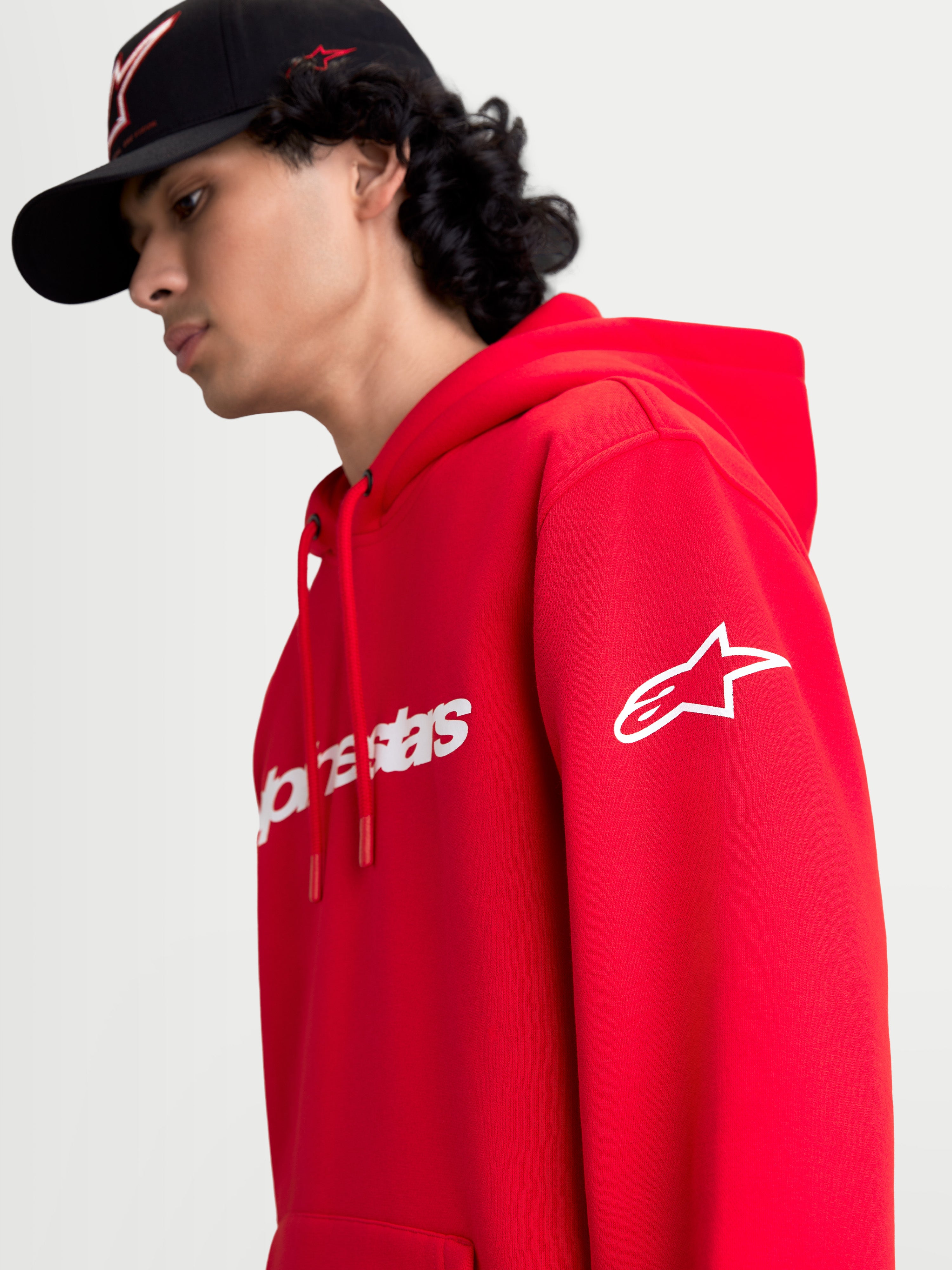 Alpinestars Race Wordmark Hættetrøje, rød og hvid sportswear fleece-hættetrøje, on-model visning med hvidt Alpinestars Ageless-logo på ærmet og Race Linear-branding på fronten, afslappet motorsportsinspireret design.